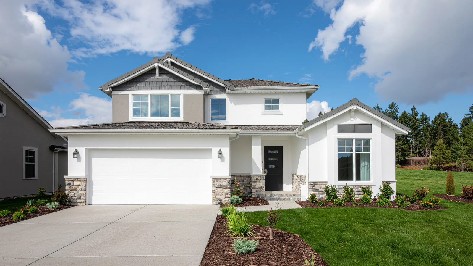 Two-story home with gray shingle roof and stone accent columns